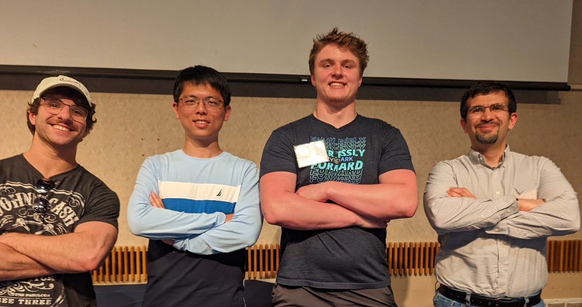 Three students and a professor stand in a row, smiling